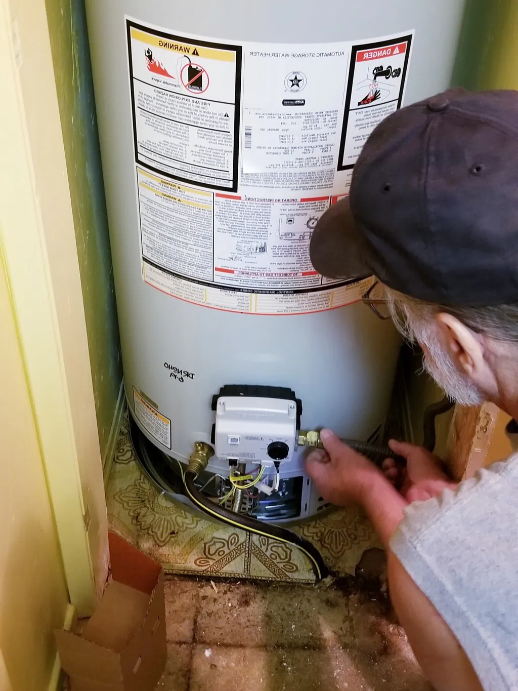 Plumber checking an old water heater in a utility closet