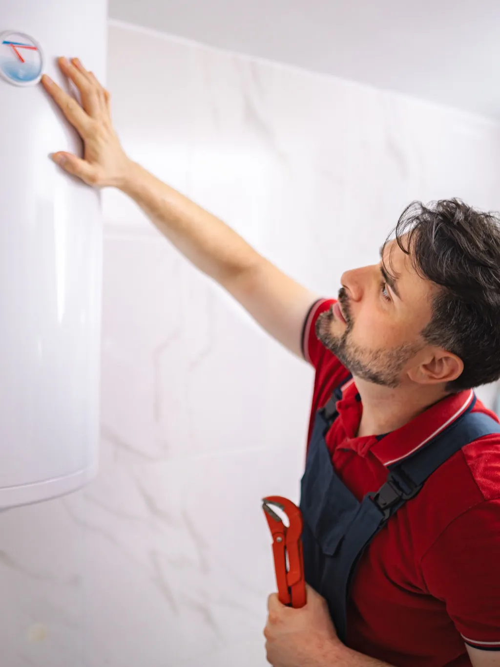Plumber adjusting a wall-mounted water heater in a bright bathroom