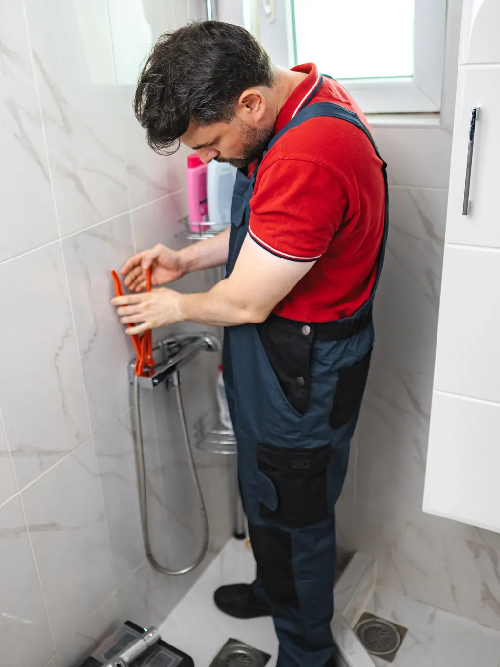 Plumber replacing a shower valve in a tiled shower