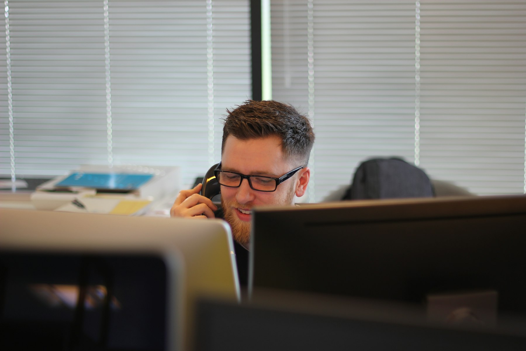A person taking a phone call at a desk in a bright open office